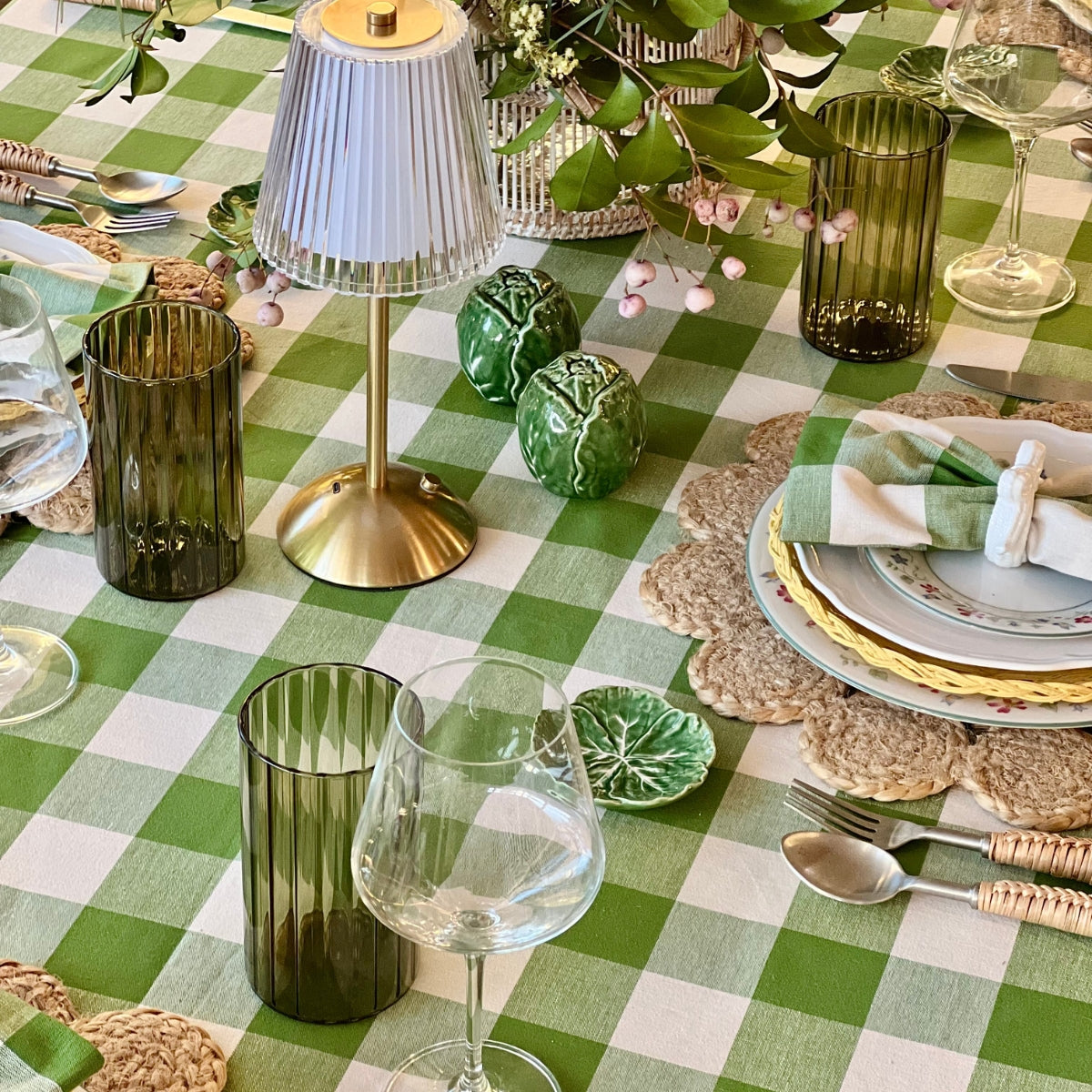 Elegant table setting with green and white checkered tablecloth, glassware, and decorative elements.