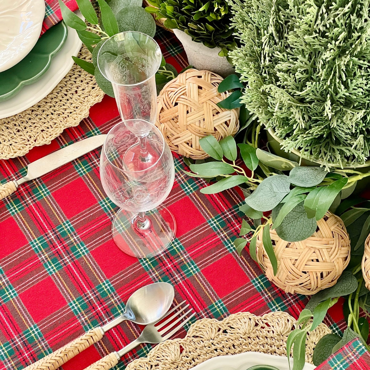 Decorative table setting with red plaid tablecloth, greenery, and wicker balls.