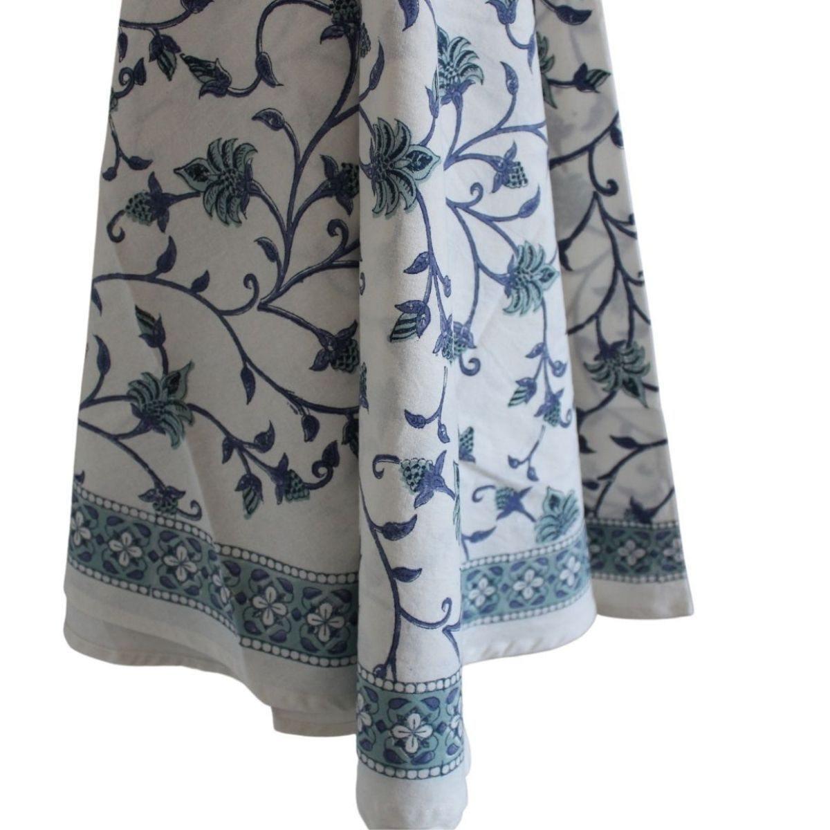 Close up of a circular dining table linen featuring a blue and green floral hand block printed pattern
