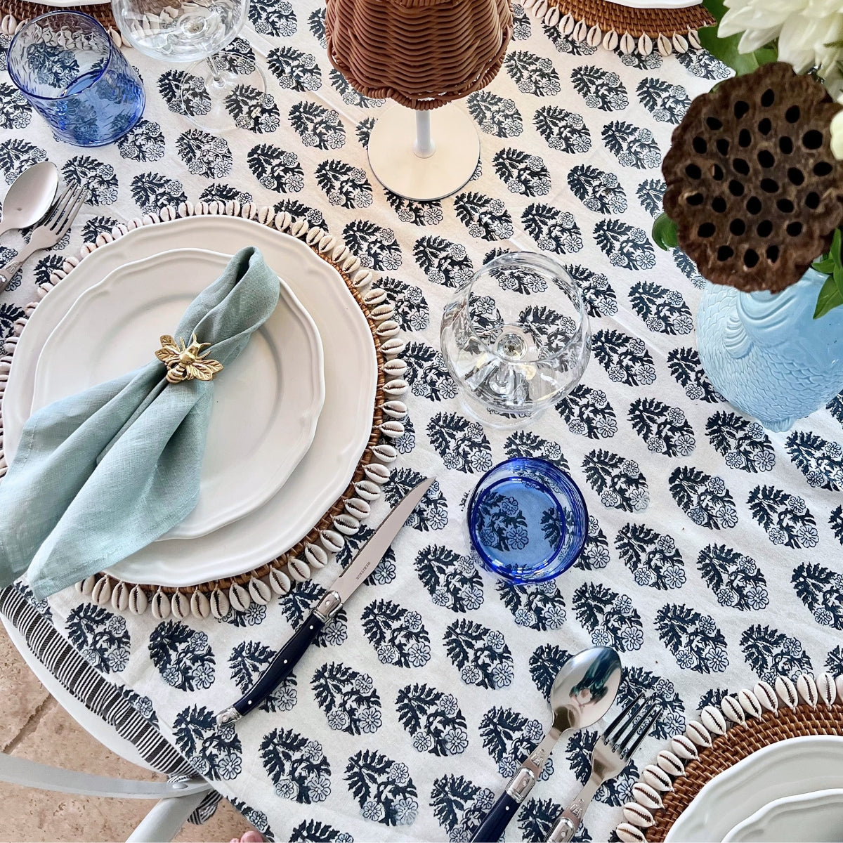 Blue and white boota hand block printed tablecloth in 152 x 225 cm set for a six seater lunch with sage napkins and a blue glass at each place