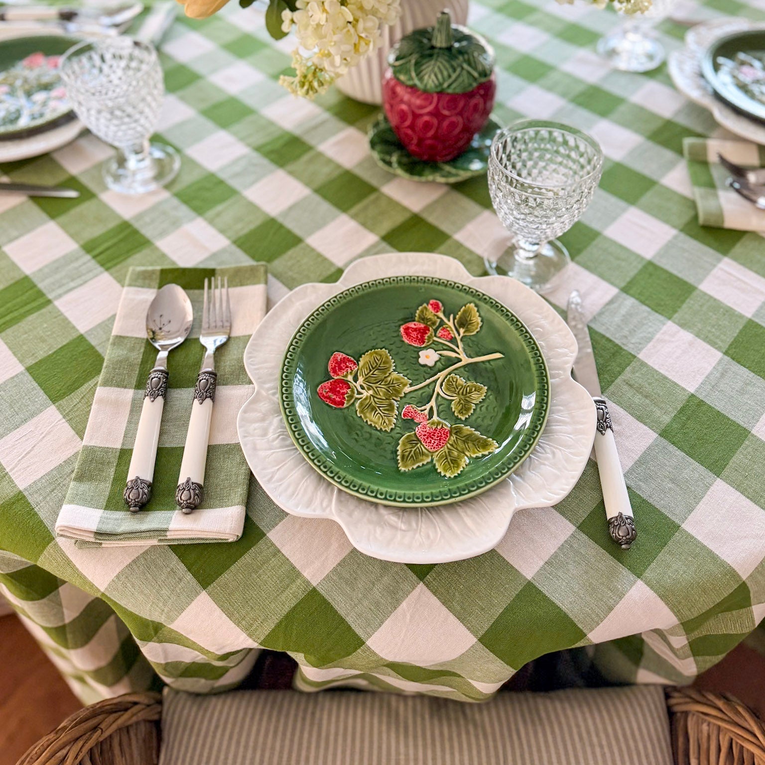 Decorative table setting with a green and white checkered tablecloth, floral centerpiece, and patterned plates.