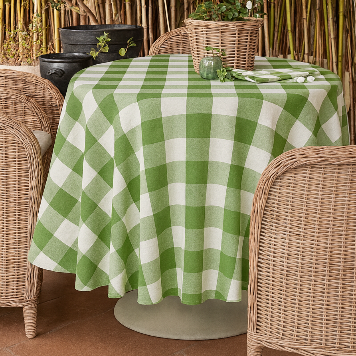 Green and white checkered tablecloth on a round table with wicker chairs.