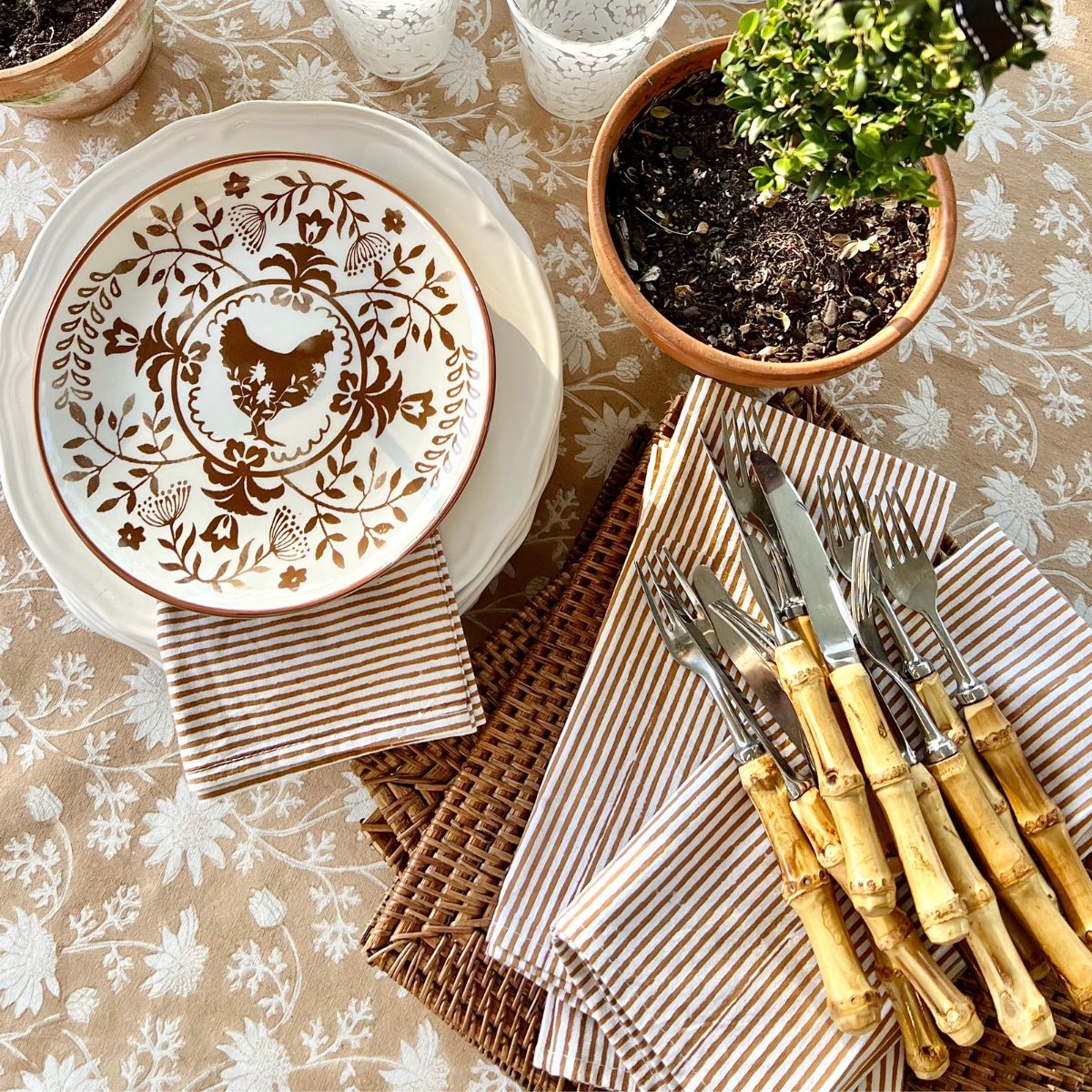 Set of 4 brown striped cotton napkins hand block printed by artisans, folded on a coordinating light brown tablecloth for everyday dining and seasonal entertaining.