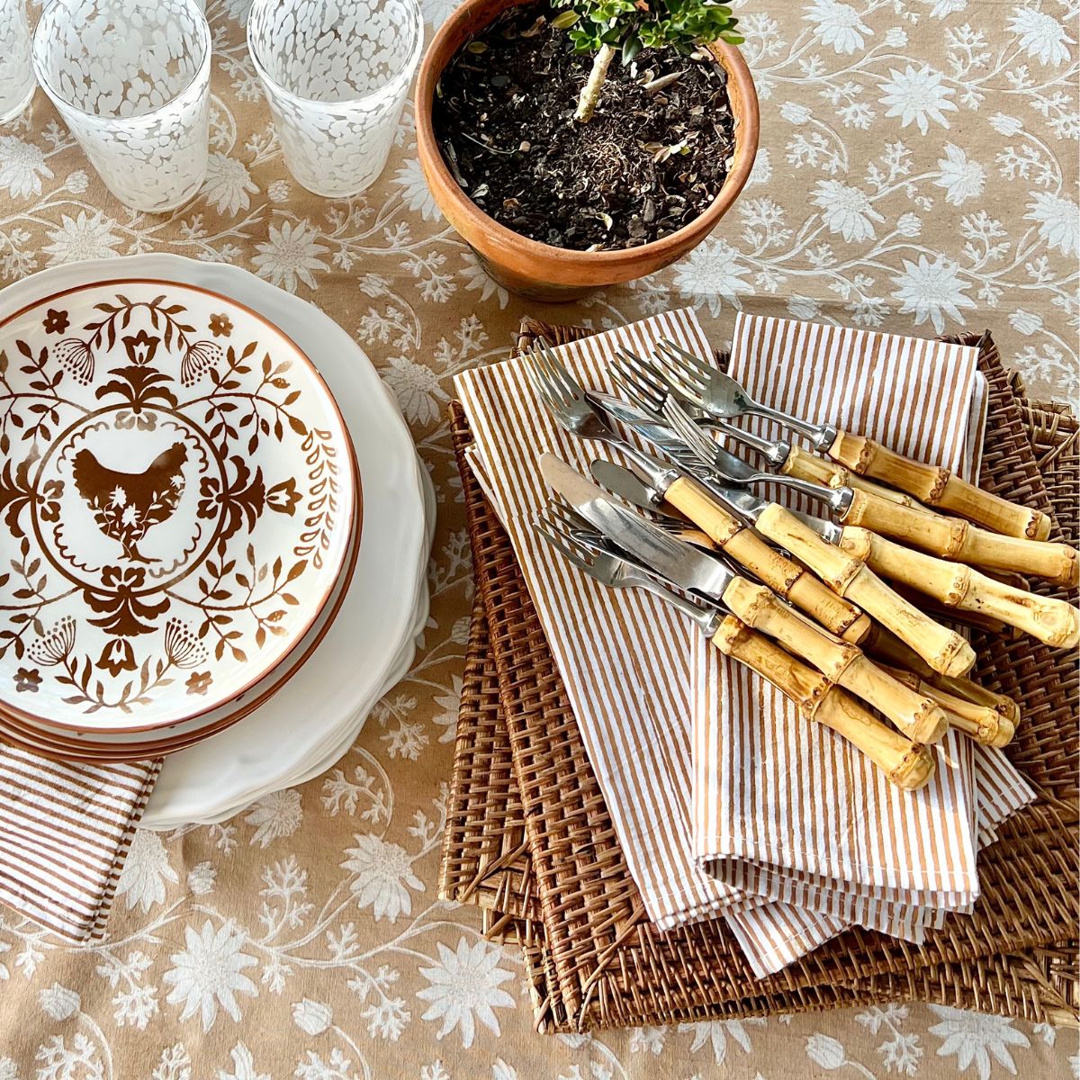 Brown striped hand block printed napkin set of 4 made of pure cotton. Displayed on a brown tablecloth table with potted plant, bamboo cutlery and brown china dishes.