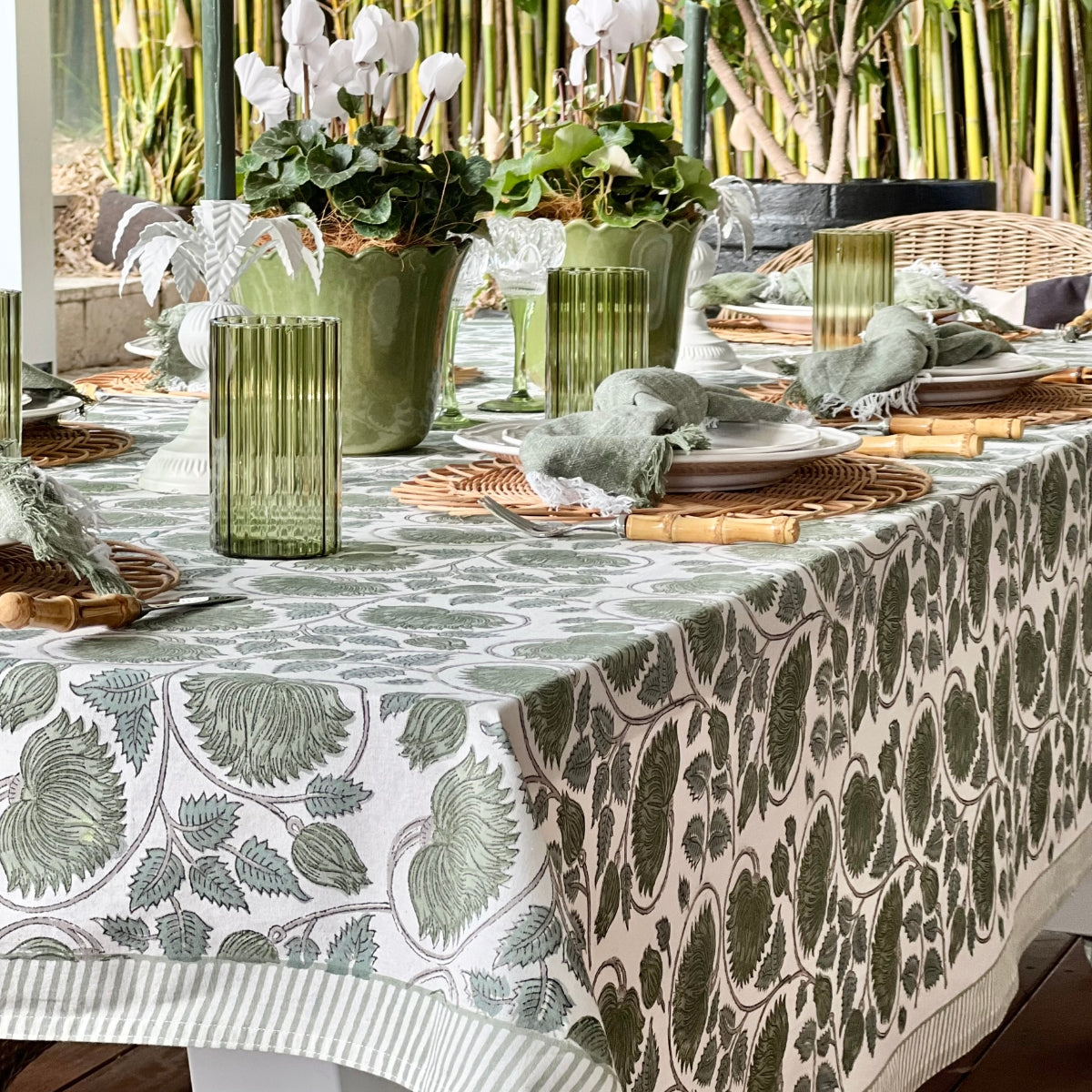 A 150 x 280 cm green lotus hand block printed rectangular table linen on a 6 to 8 seater table, set for a relaxed casual lunch with a fresh botanical feel.
