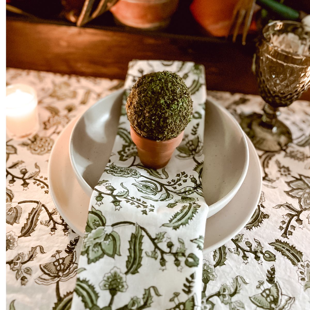A set of green and white hand block printed chintz floral patterned napkins on a dining table.