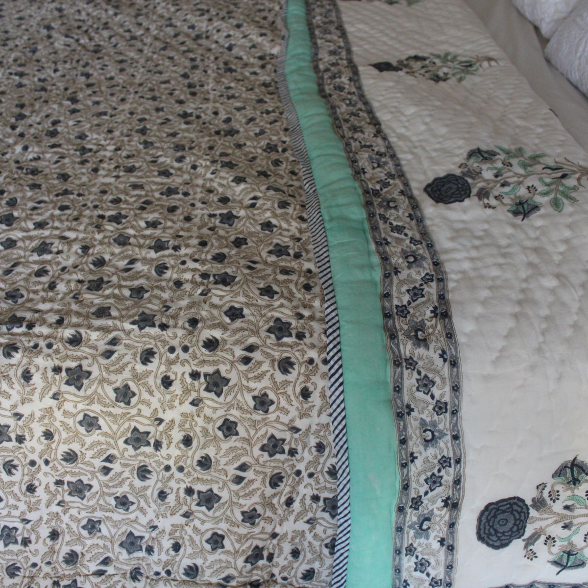Hand block printed reversible cotton quilt with blue and green floral motifs and floral jaal pattern, hand quilted by Indian artisans and designed for year-round comfort.