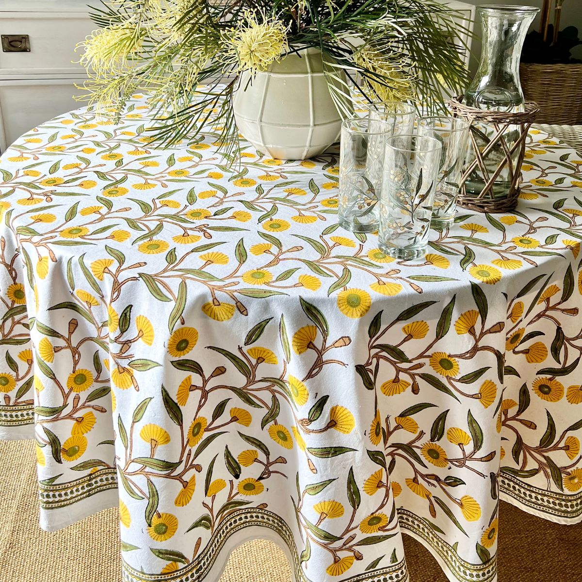 Yellow Flowering Gums round tablecloth paired with décor accents and floral centrpiece for a vibrant indoor tablescape.