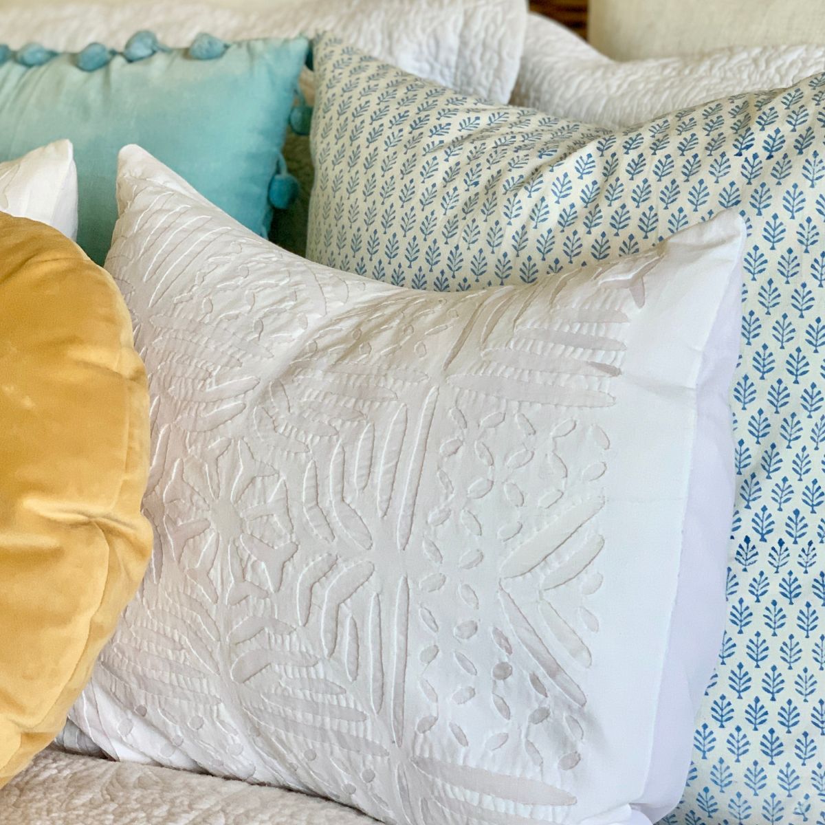 white applique cut sewn cushion cover displayed on bed