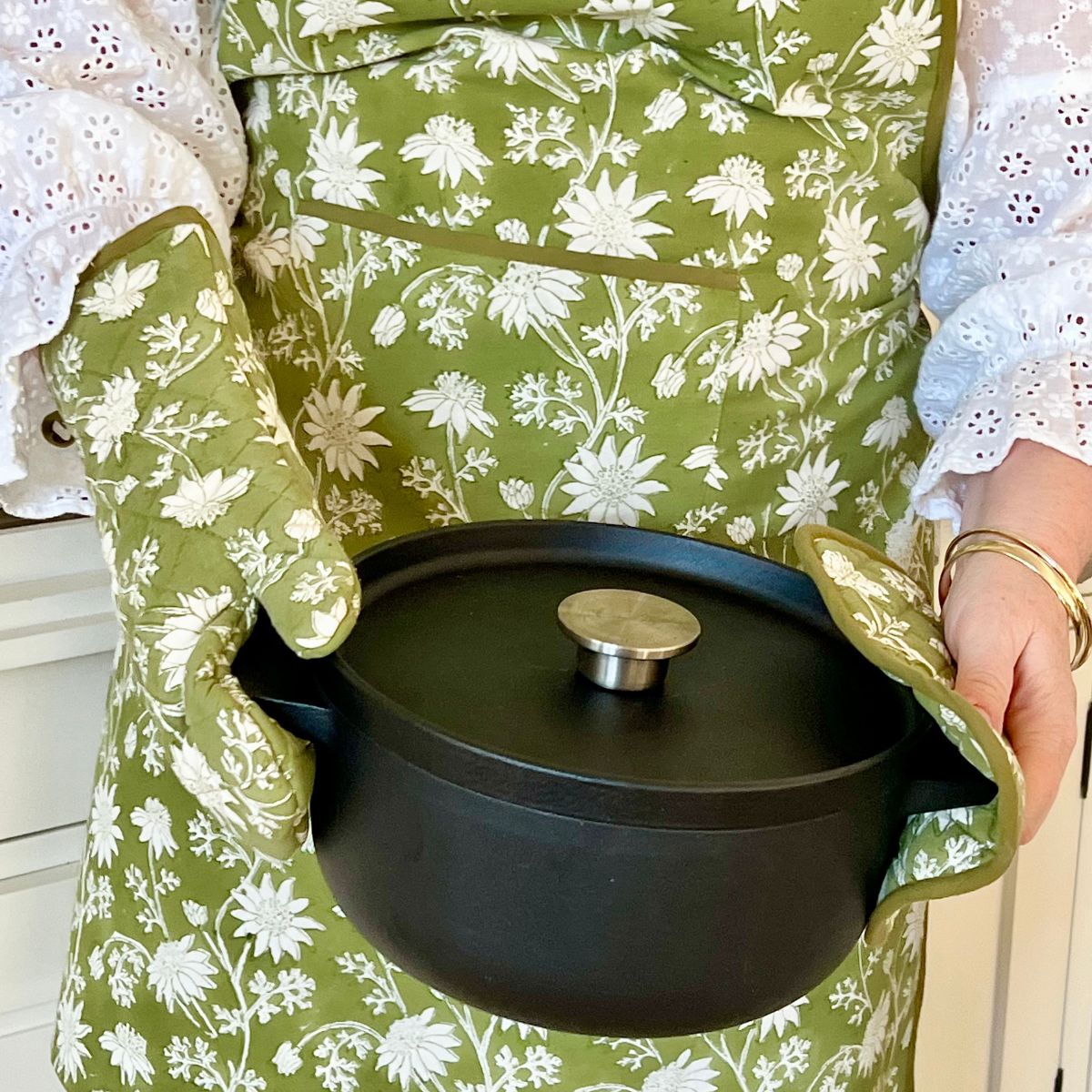 Flannel Flowers apron, oven mitt, and pot holder styled together in a working kitchen, highlighting coordinated floral block prints and practical everyday use.