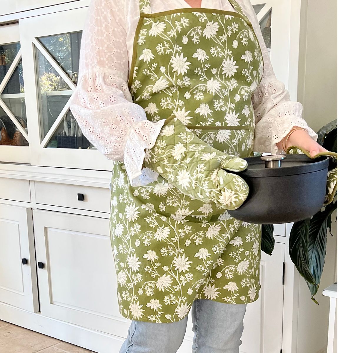 Hand block printed apron, oven mitt, and pot holder from the Flannel Flowers collection displayed during meal preparation in a cozy kitchen setting.