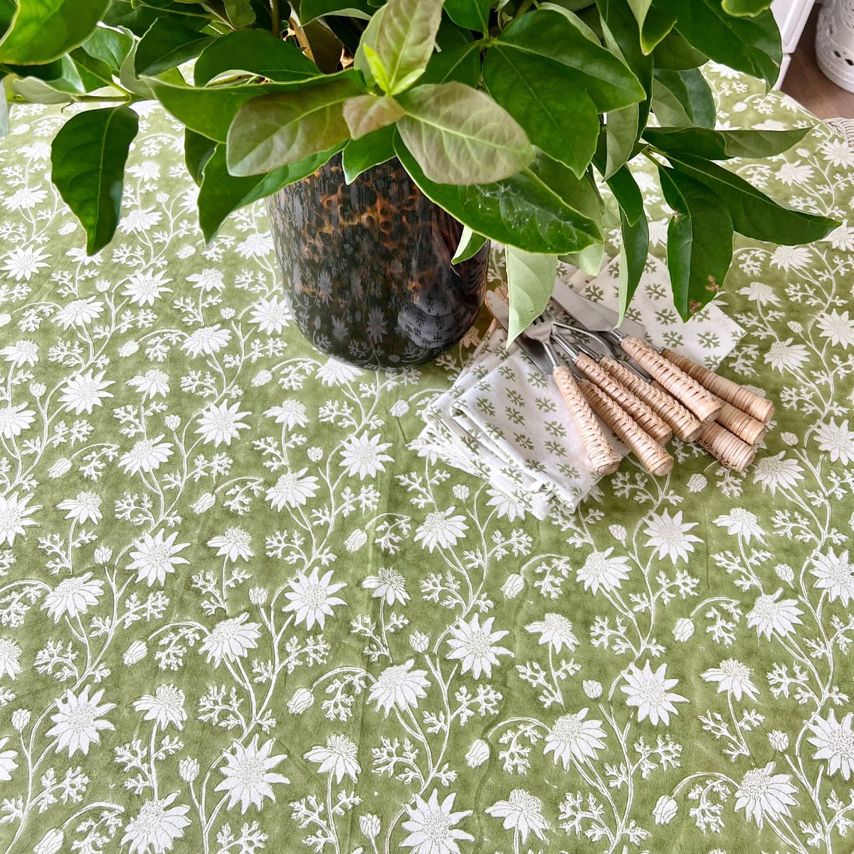 180 cm Flannel Flowers round tablecloth viewed from above with folded napkins and bamboo cutlery to be set up for relaxed everyday dining.