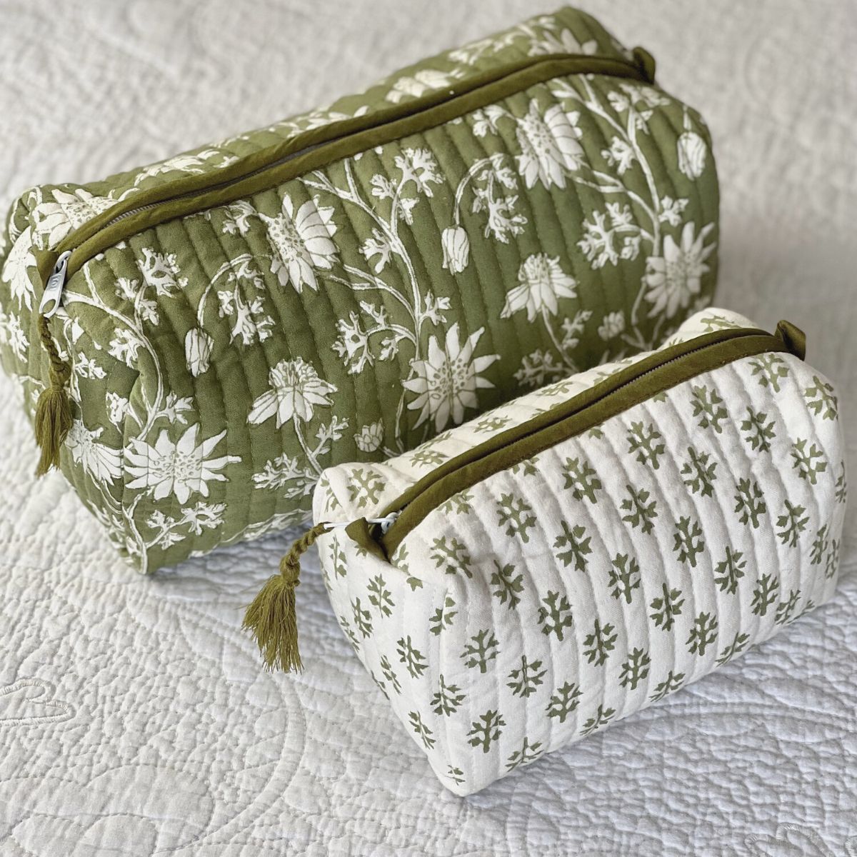 Two floral hand block printed quilted wash bags with zipper closure, one large and one small, displayed on a textured surface.