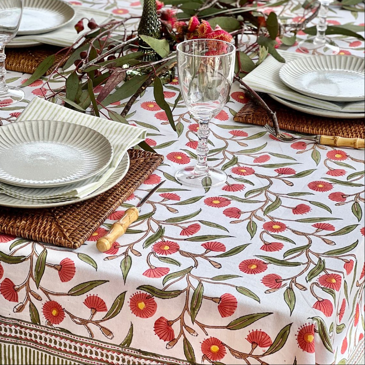 180 cm Red Flowering Gums square cotton tablecloth styled with dinnerware for casual everyday meals and family gatherings.