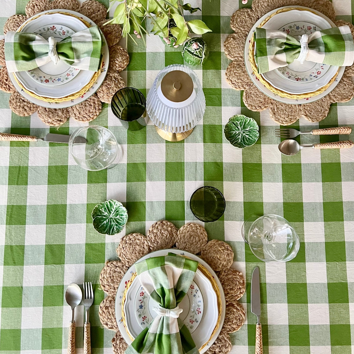 Elegant table setting with green and white checkered tablecloth, decorative plates, and cutlery.