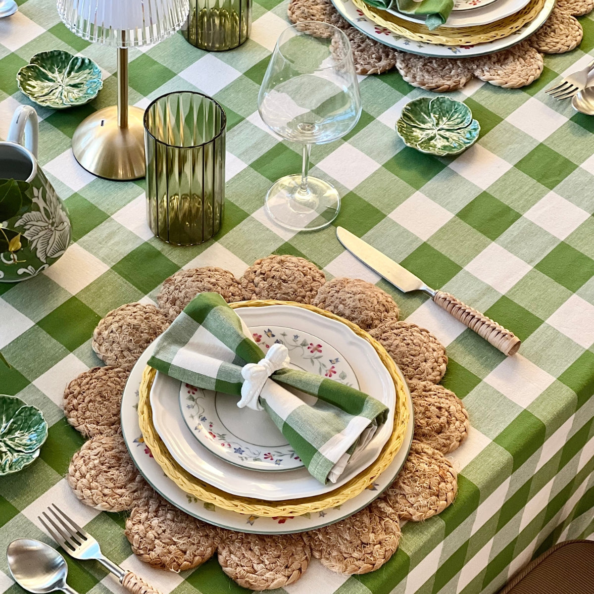 Table setting with green and white checkered tablecloth, decorative plates, and cutlery.