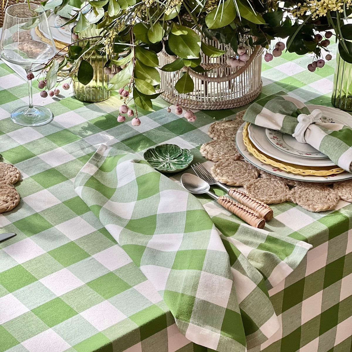 Decorative table setting with green and white checkered tablecloth, plates, and cutlery.