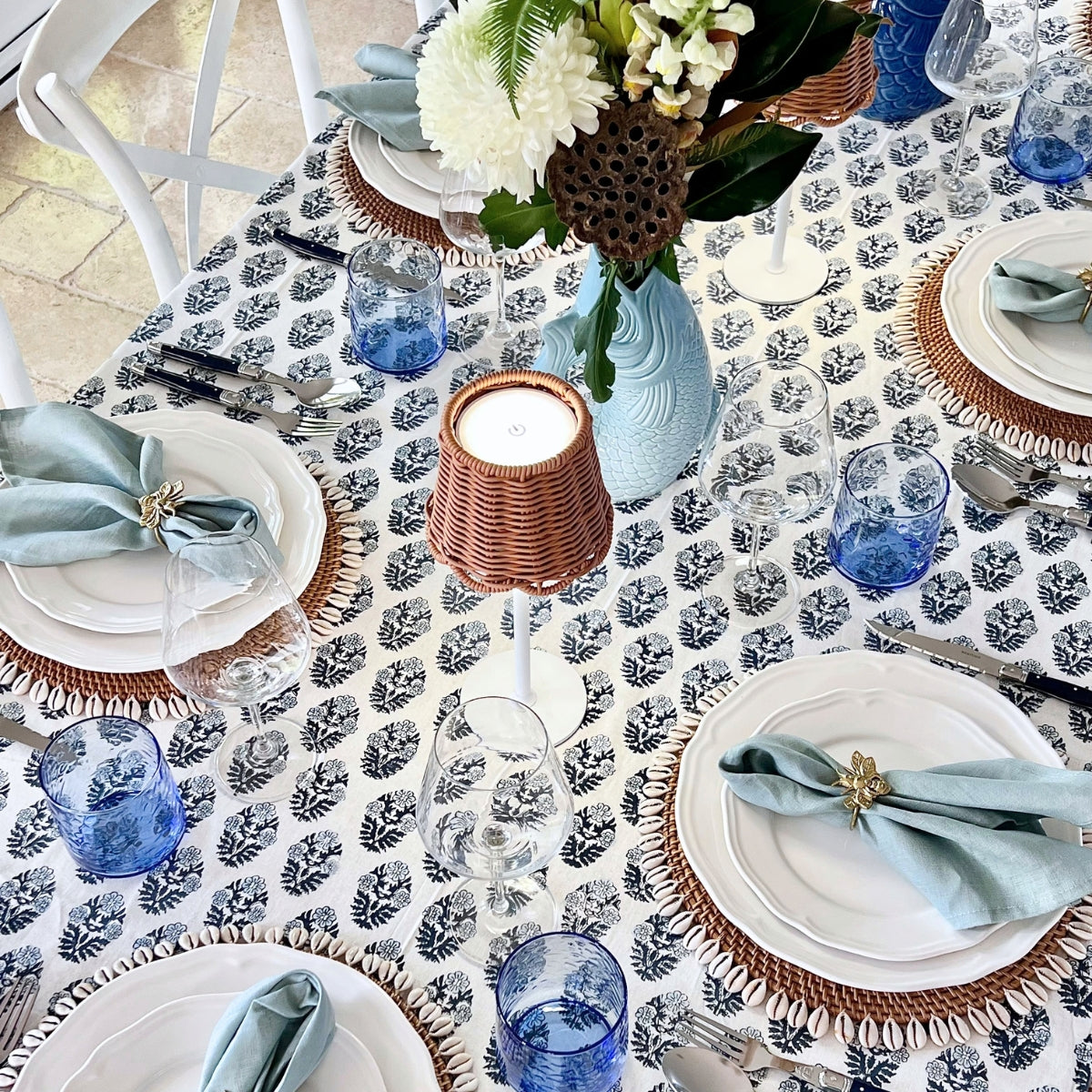 
Rectangular monochrome blue floral hand block printed tablecloth set for a casual summer lunch with sage napkins, rattan placemats and blue glassware