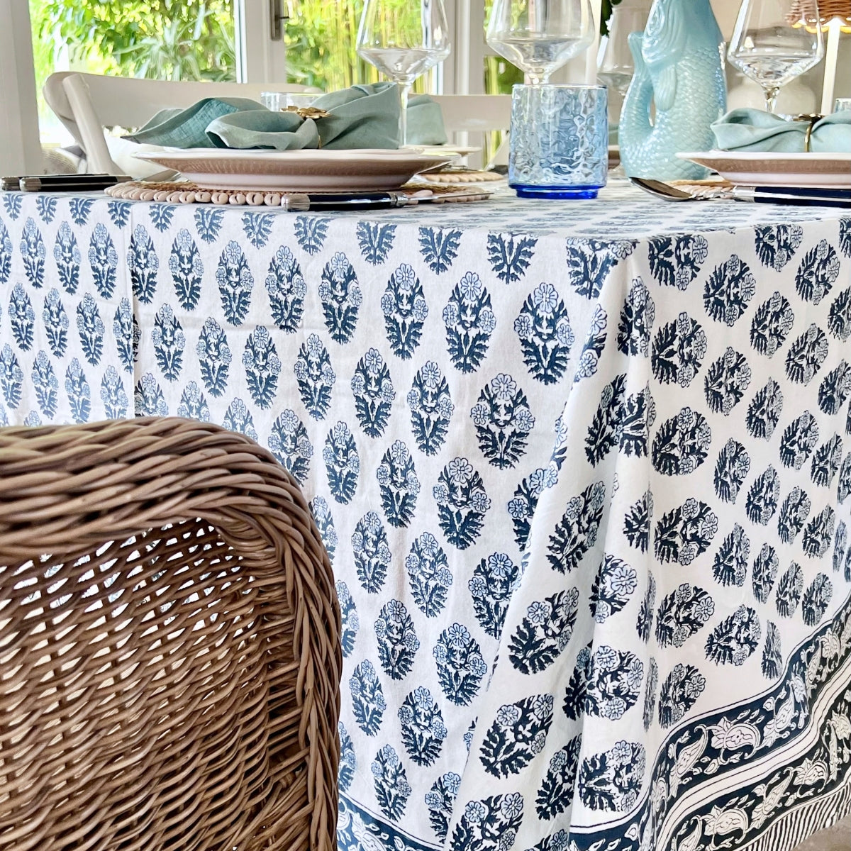 
Side view of a blue floral boota hand block printed tablecloth in 150 x 285 cm draping neatly over a table that seats 8 to 10 people