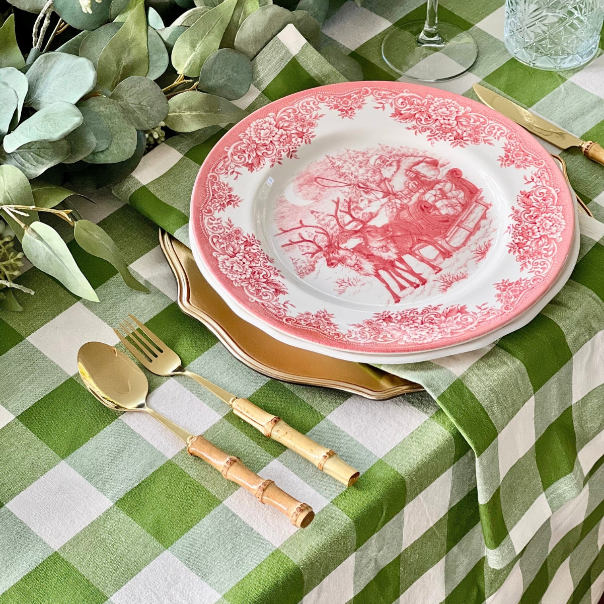 Green and white checkered tablecloth on a round table with wicker chairs.