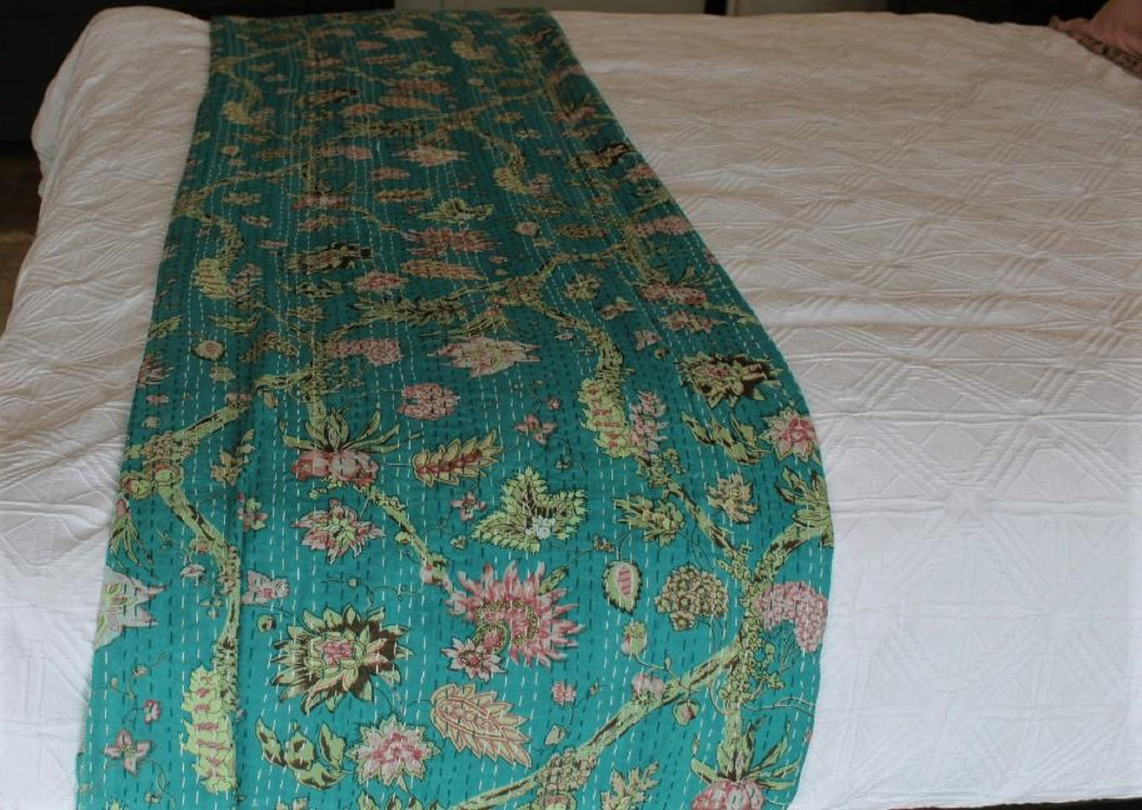 Floral-patterned quilt on a white bedspread