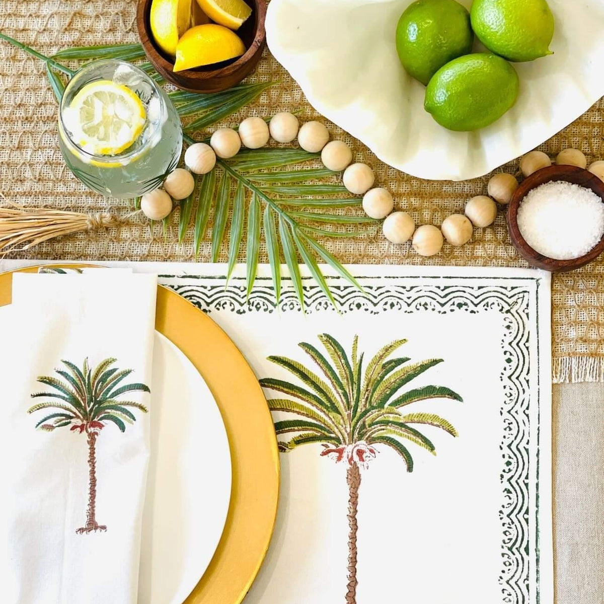 Table setting with palm tree design, lemons, limes, and a glass of water.