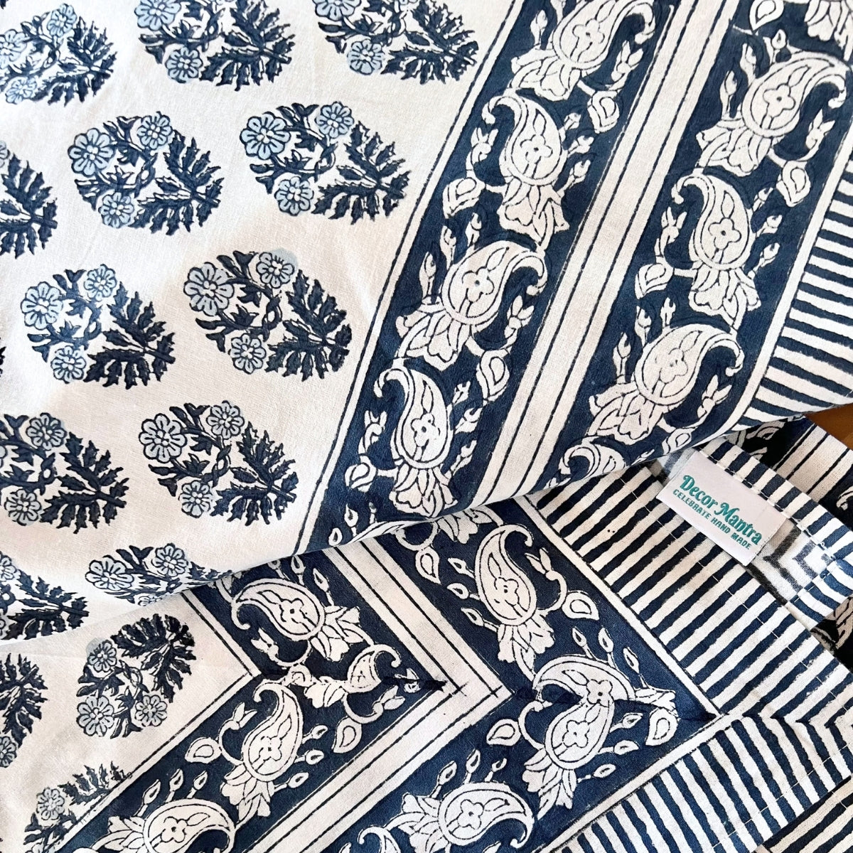 A detail shot of block printed cotton tablecover featuring floral motif and paisley border with striped edge detailing.