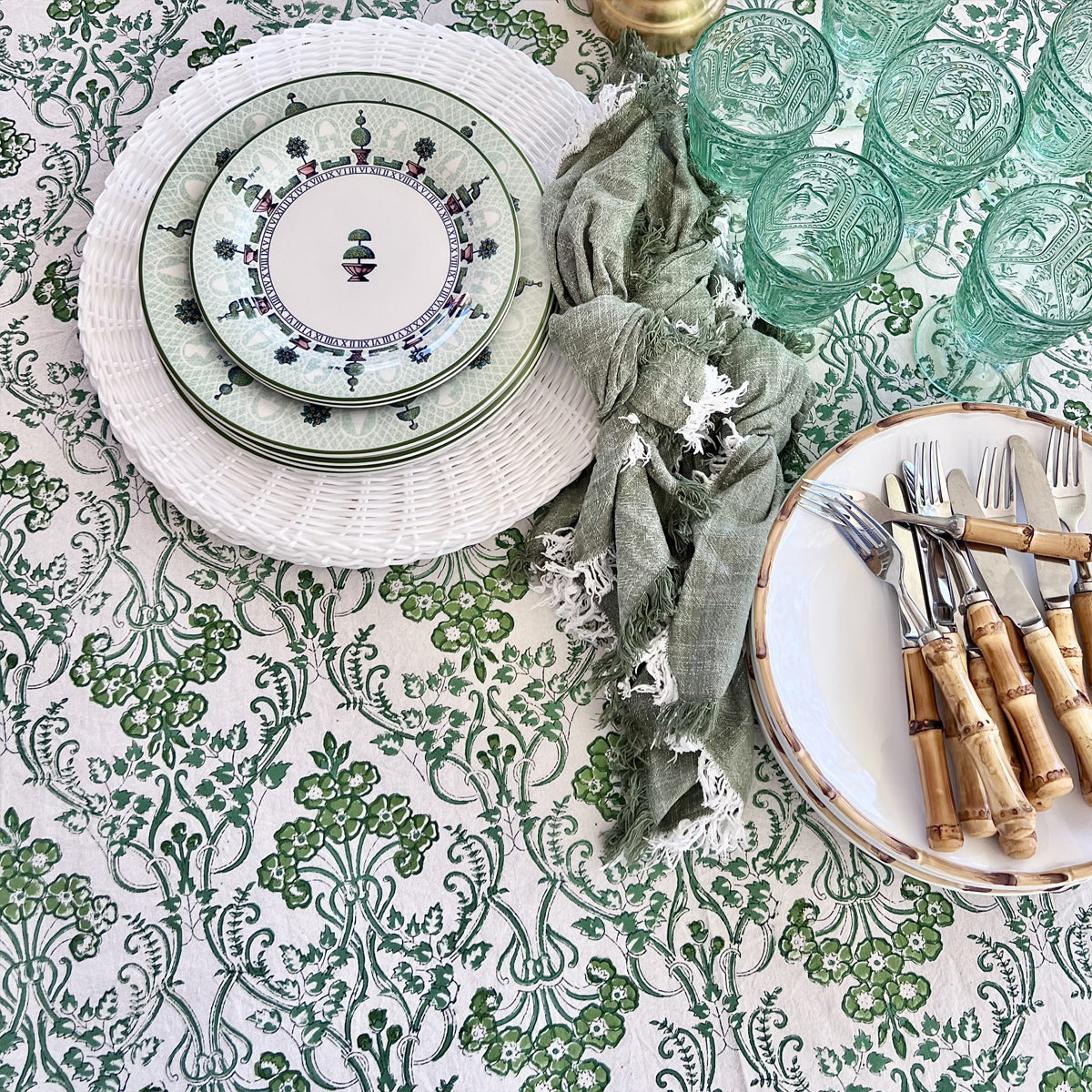 Green and white floral hand block printed tablecloth styled for all year round entertaining with a patterned plate, linen napkin and woven placemat