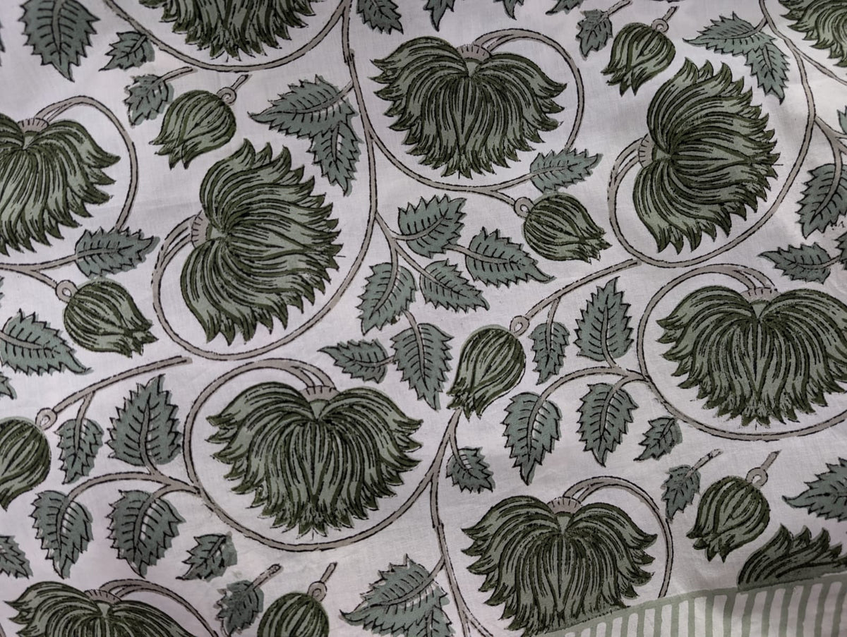 A round tablecloth with a green lotus floral pattern displayed on a table with a white edge.