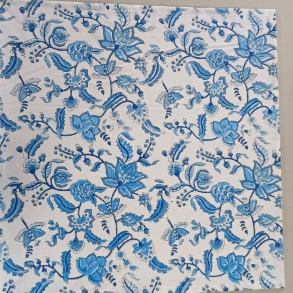 A blue chintz floral hand block printed cotton napkin from a set of 4, laid flat on a table, showing the full repeat of the intricate chintz floral motif on premium cotton fabric.