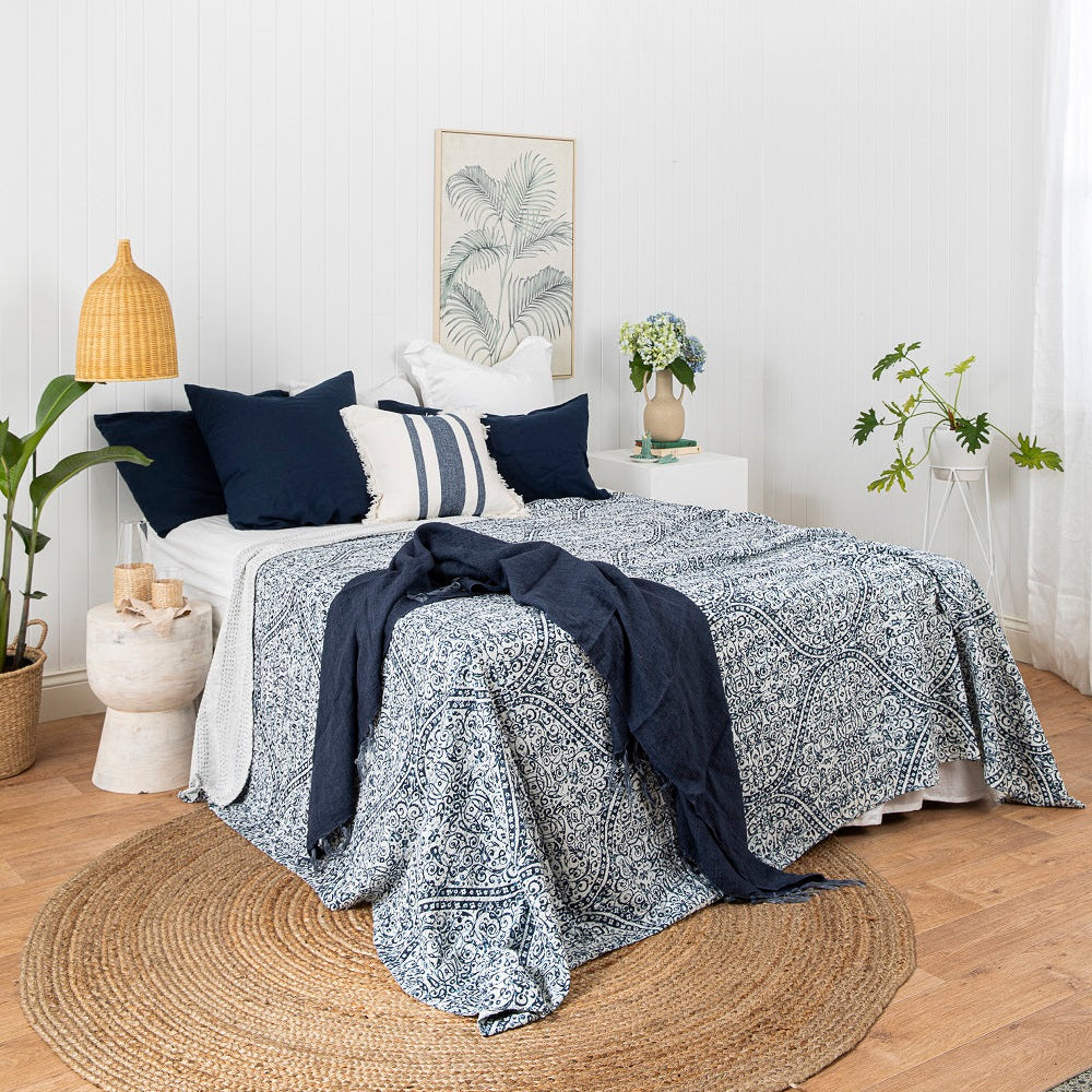 Bedroom with a bed covered in blue and white patterned bedding, surrounded by decorative elements.