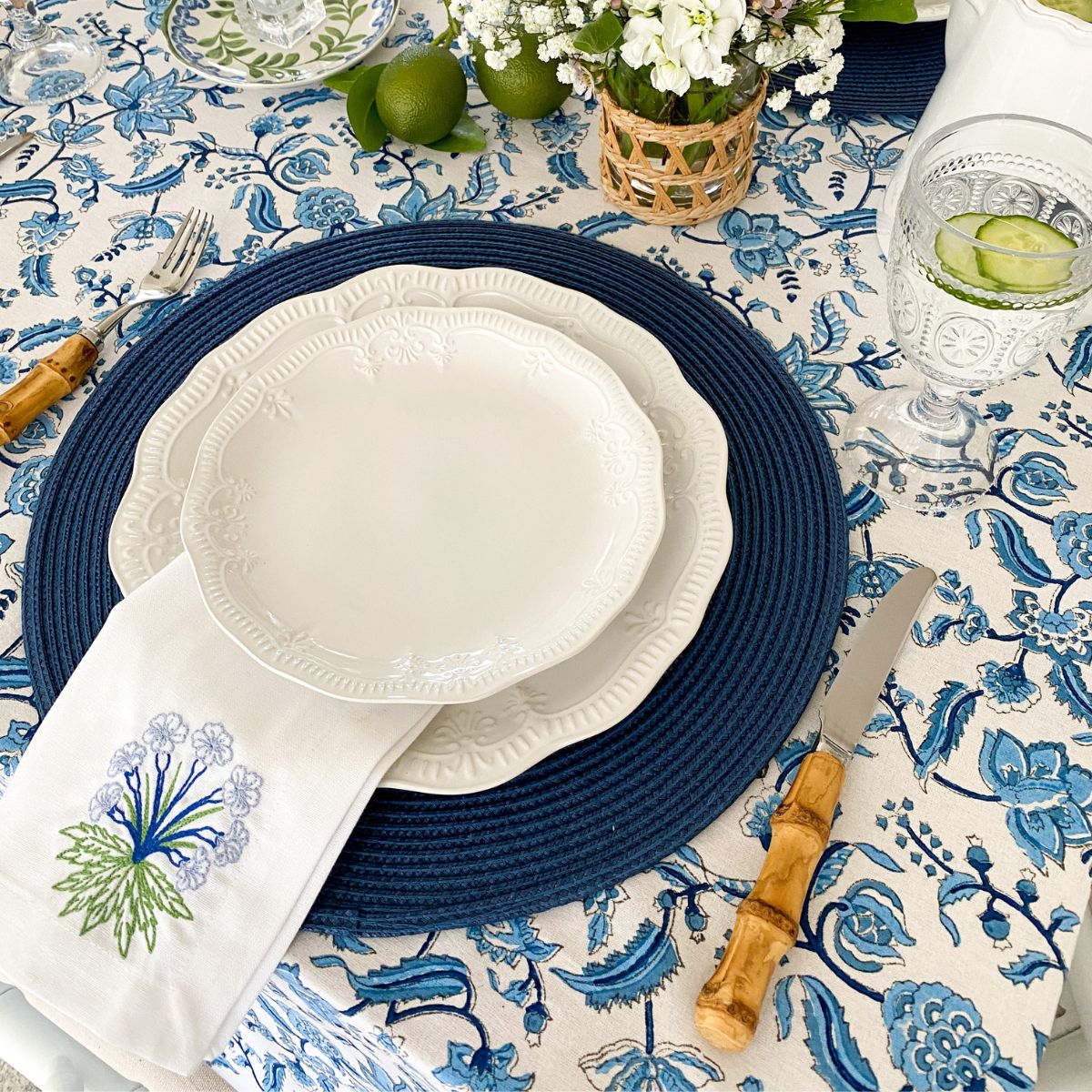 A blue and white hand block printed chintz floral patterned square tablecloth on a dining table.