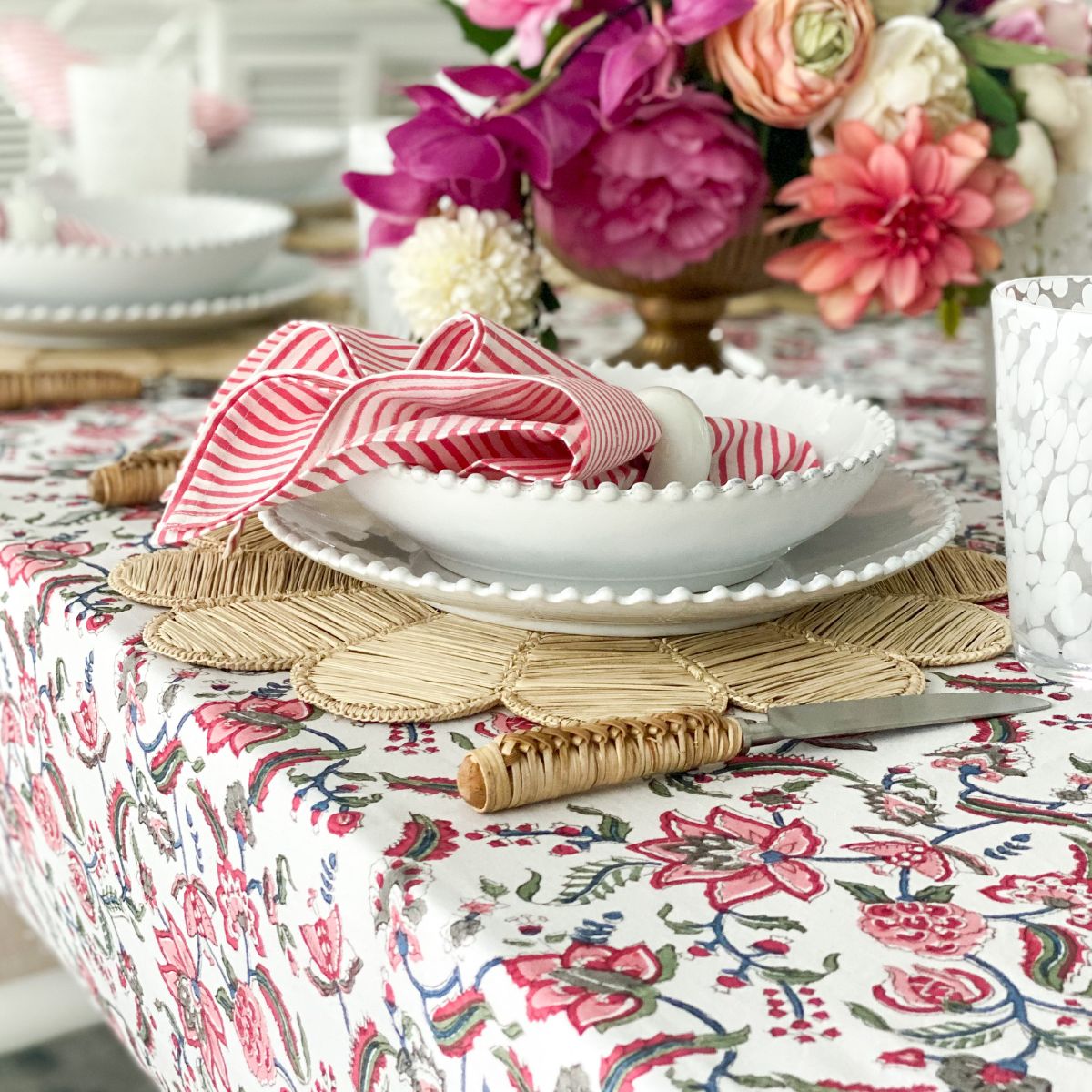 
A 220 x 220 cm Chintz multicoloured hand block printed square table linen for an 8 seater special occasion dining table, the blazing red pomegranate and complementary border creating a rich vibrant tablescape.