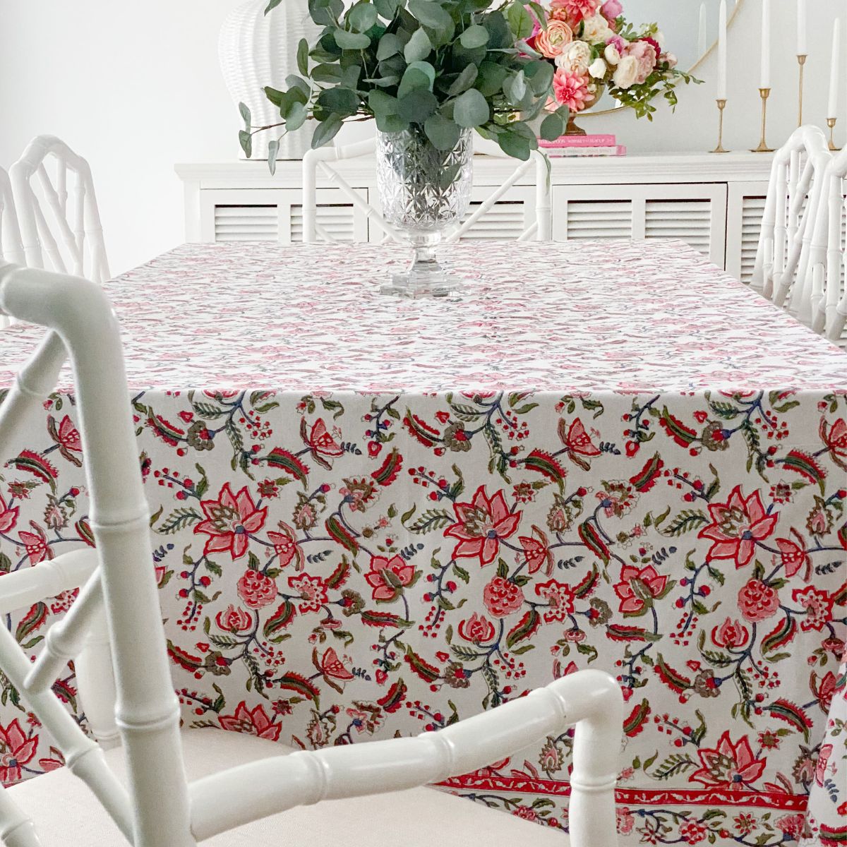 
A 180 x 180 cm Chintz multicoloured hand block printed cotton square tablecloth on a 6 seater dining table, styled with a floral vase, a vibrant everyday tablecover that makes every meal feel special.