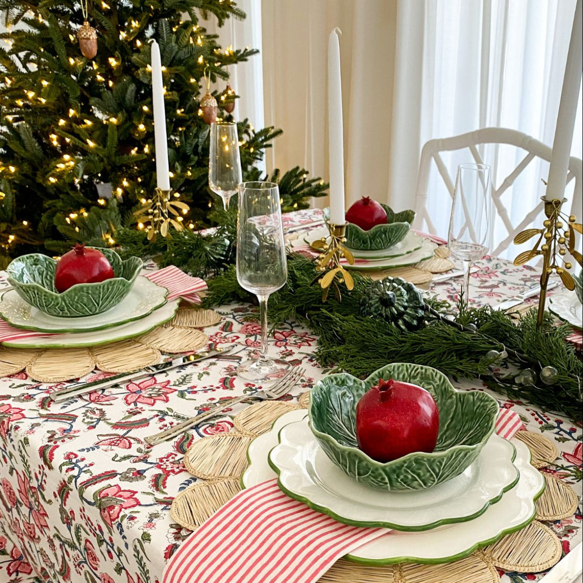  Chintz multicoloured hand block printed cotton tablecloth on a 6 seater Christmas table, dressed with greenery, Christmas tree ornaments, and pomegranate-styled dishes for a rich and vibrant festive tablescape.