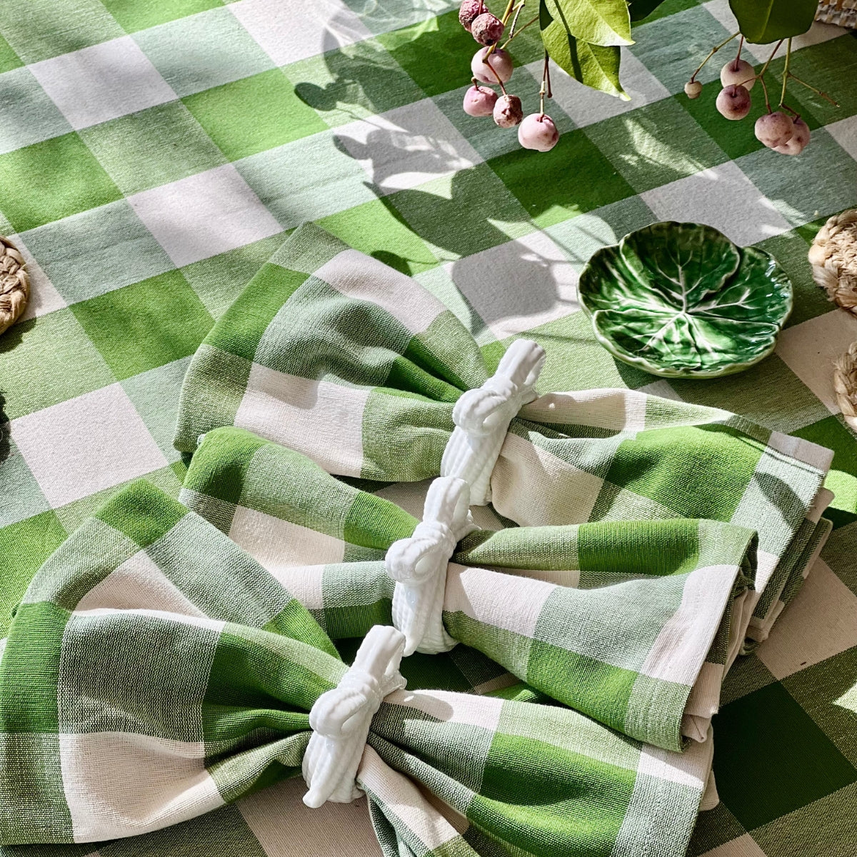 A close-up of  45 x 45 cm green gingham check handwoven cotton napkin set, folded in napkin rings. Showing the woven check pattern and the weight and texture of the premium heavy duty cotton,crafted by skilled weavers in Kerala, India.