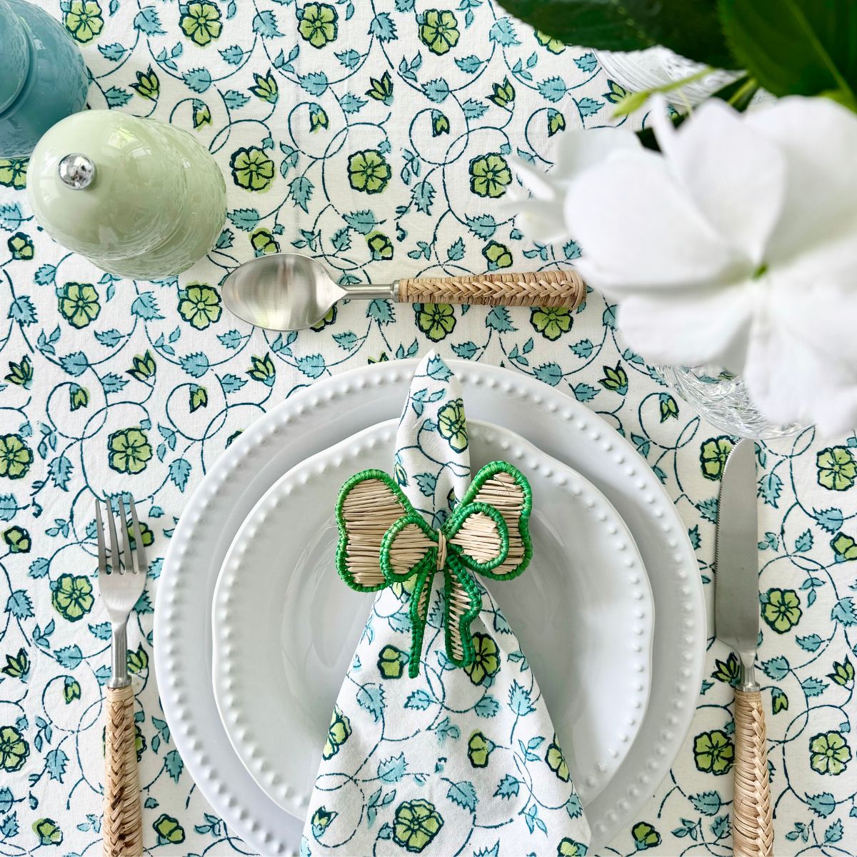 
Green bow napkin ring styled with a napkin, white dinnerware, and a blue green floral tablecloth, creating a festive tablescape for a summer Christmas celebration and special occasions.