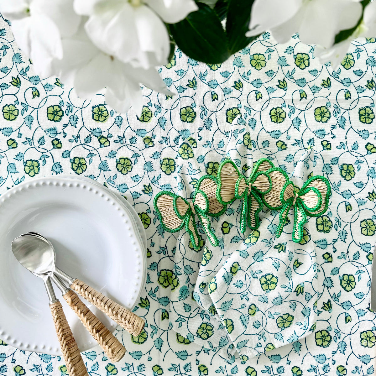 
Handwoven green bow napkin rings arranged with cutlery, plates, and napkins on a table ready to be set, perfect for holiday entertaining, Christmas dinners, and festive gatherings