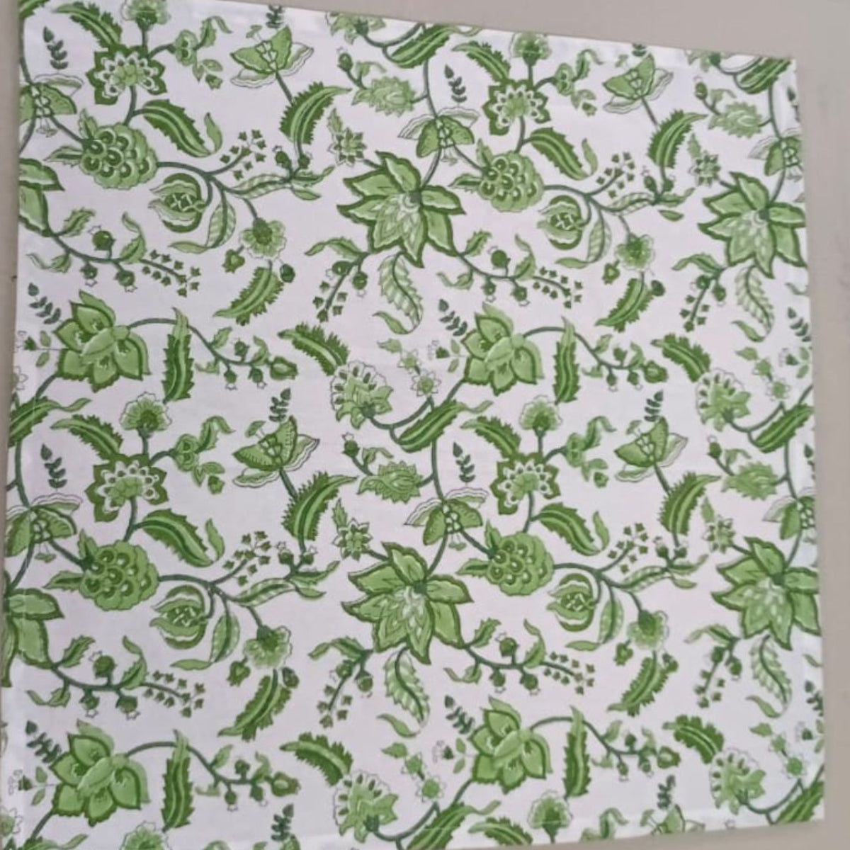 A green chintz hand block printed cotton napkins laid flat on a table, showing the full intricate chintz floral pattern and the natural texture of the premium cotton fabric.