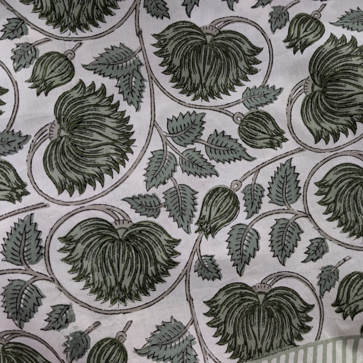 A close-up of the green lotus hand block printed cotton tablecloth showing the intricate floral lotus motif, the natural variation in print depth characteristic of small batch artisan block printing.