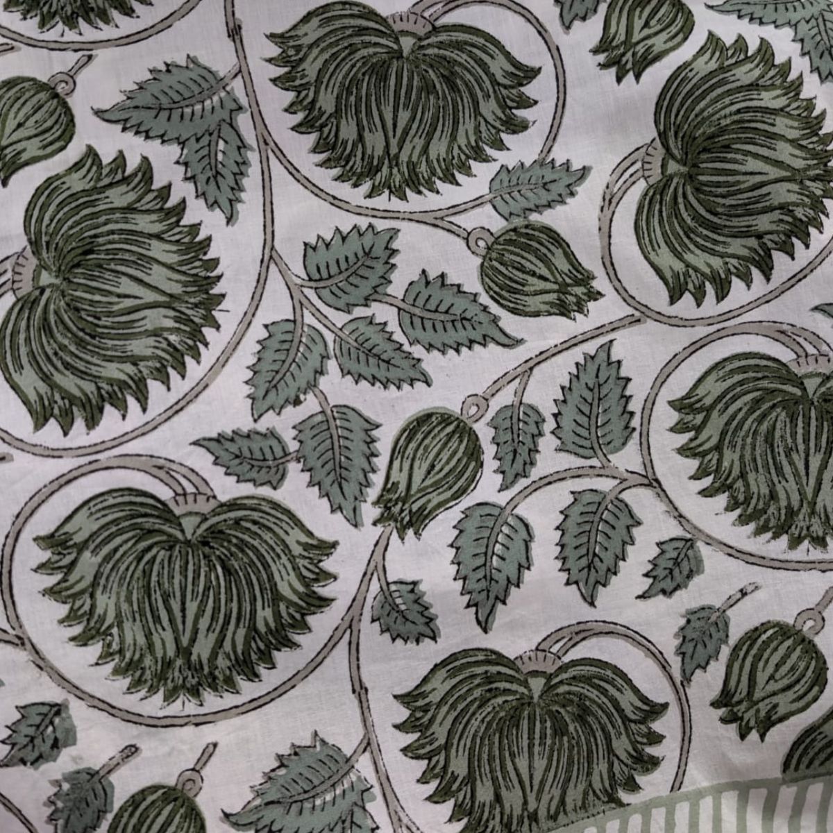 A close-up of the green lotus hand block printed tablecloth showing the subtle look of the green floral lotus print and the natural texture of the premium cotton fabric.