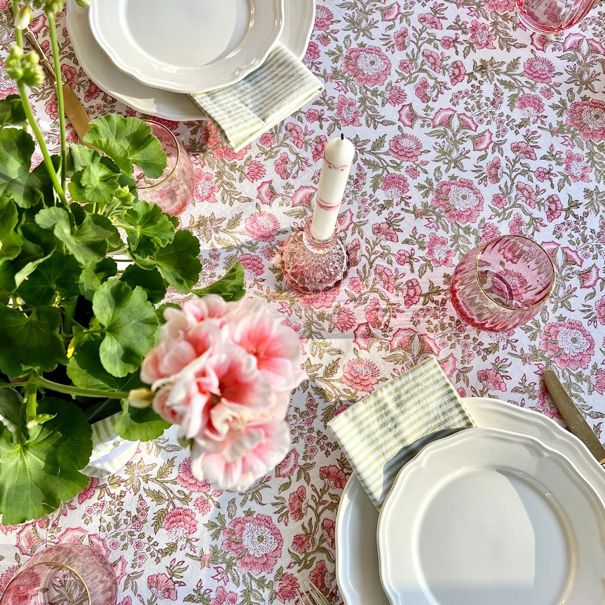 
Hand block printed green striped napkins styled over white dishes on a coordinating pink and green floral tablecloth for casual entertaining and family gatherings.