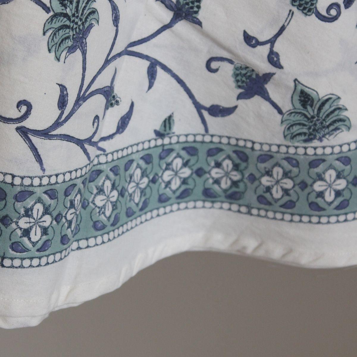 Close up of the hand block printed border of a circular dining tablecloth with a blue and green floral  hand block printed pattern
