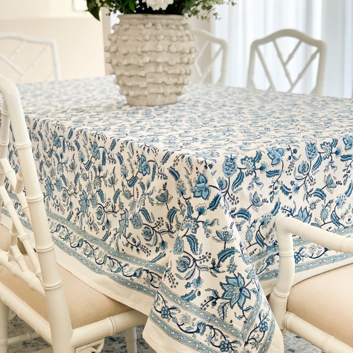 A tablecloth with a traditional hand block printed Indian chintz pattern in blue and white, displayed on a table.