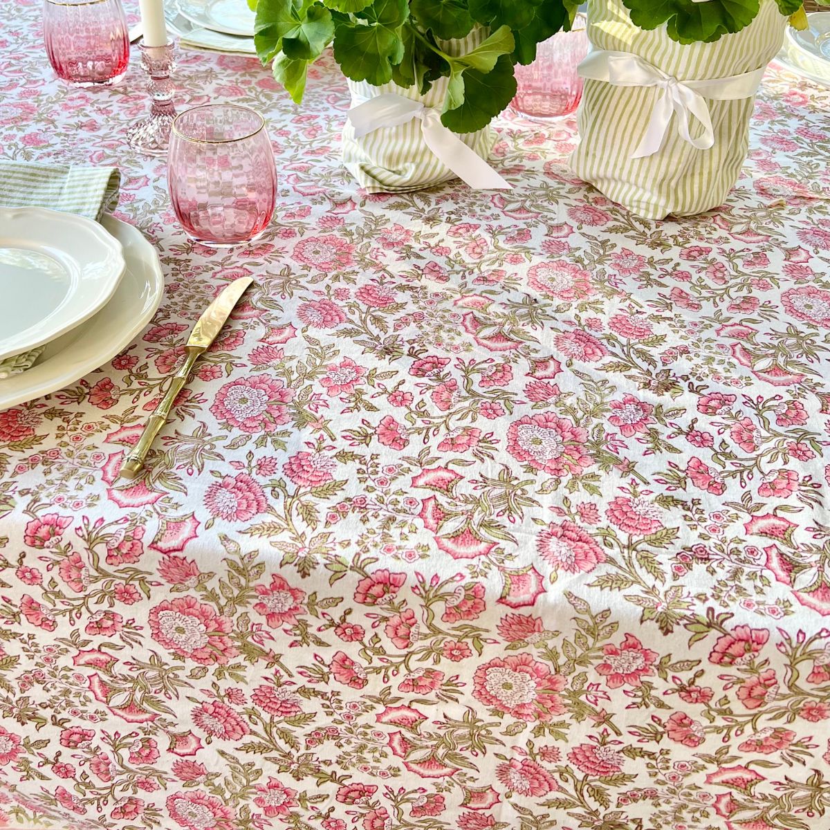 A close up of square hand block printed tablecloth in a pink and green Beatrice design set for a sunday brunch with friends