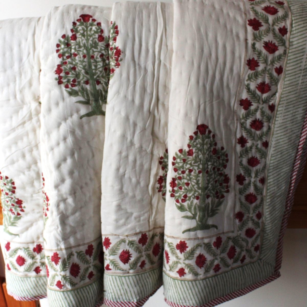 
Ruby reversible cotton quilt styled with breakfast in bed and a coffee tray, featuring vibrant red and green floral block prints for a cozy morning retreat.