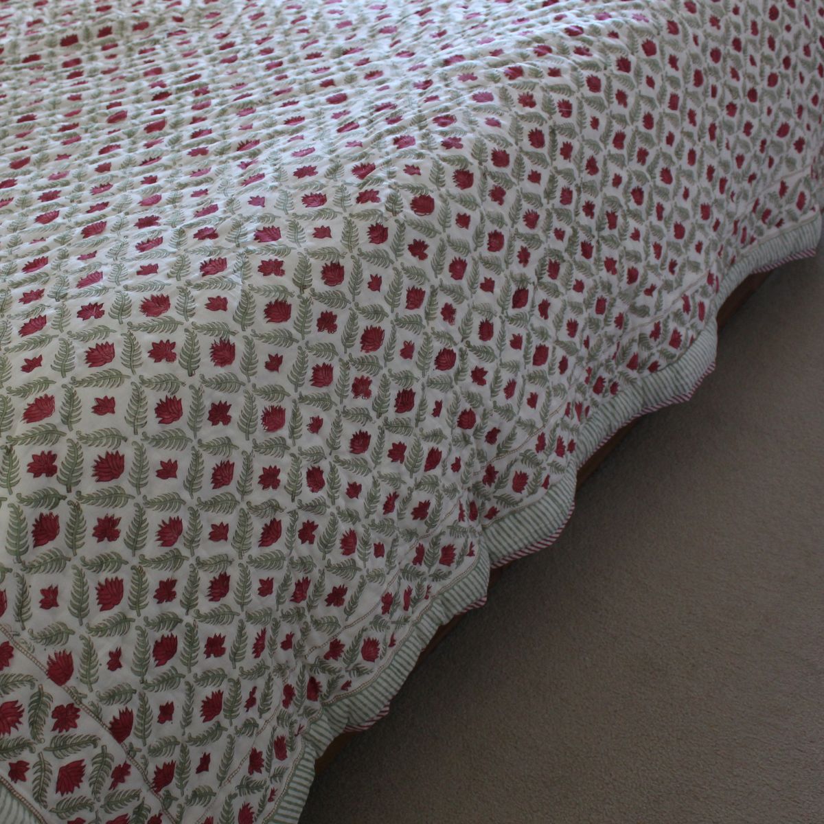 Handcrafted cotton quilt featuring intricate red floral motifs, traditional block printing, and lightweight comfort for year-round use.