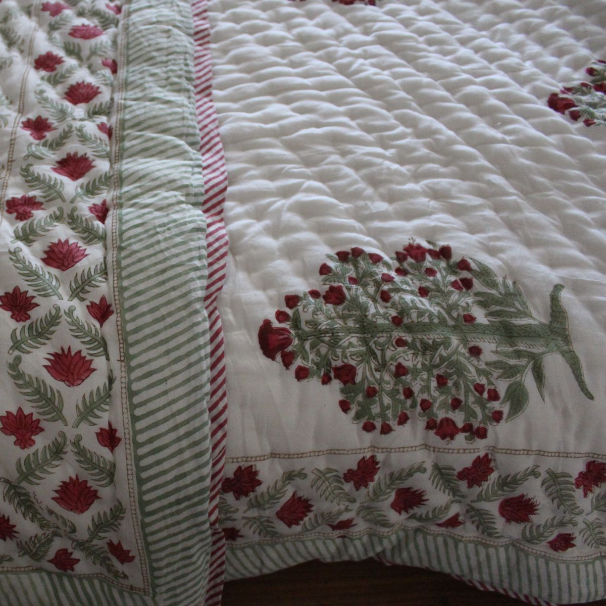 
Reversible cotton quilt showcasing a stunning red and green floral pattern on one side and a traditional heritage boota print on the reverse for two distinct bedding looks.