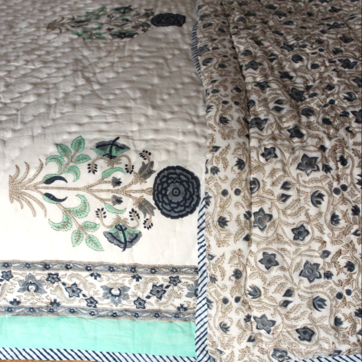 Lightweight all-season Stella cotton quilt on a queen bed featuring blue, green, and beige floral block print patterns handcrafted by Rajasthan artisans.