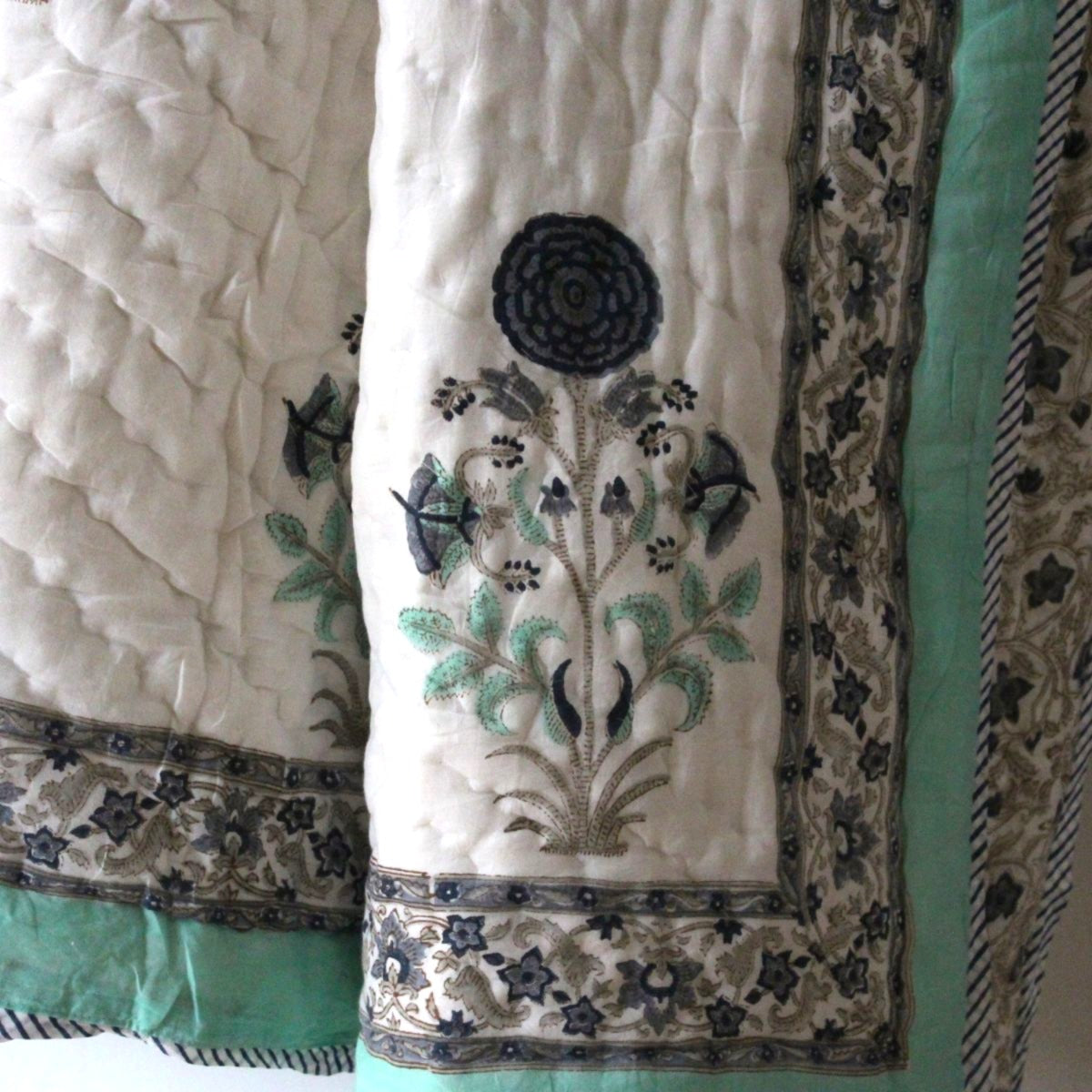 Queen-size Stella reversible cotton quilt zoomed in, showcasing traditional Indian floral block print motifs and border on hand embroidered breathable cotton voile fabric.